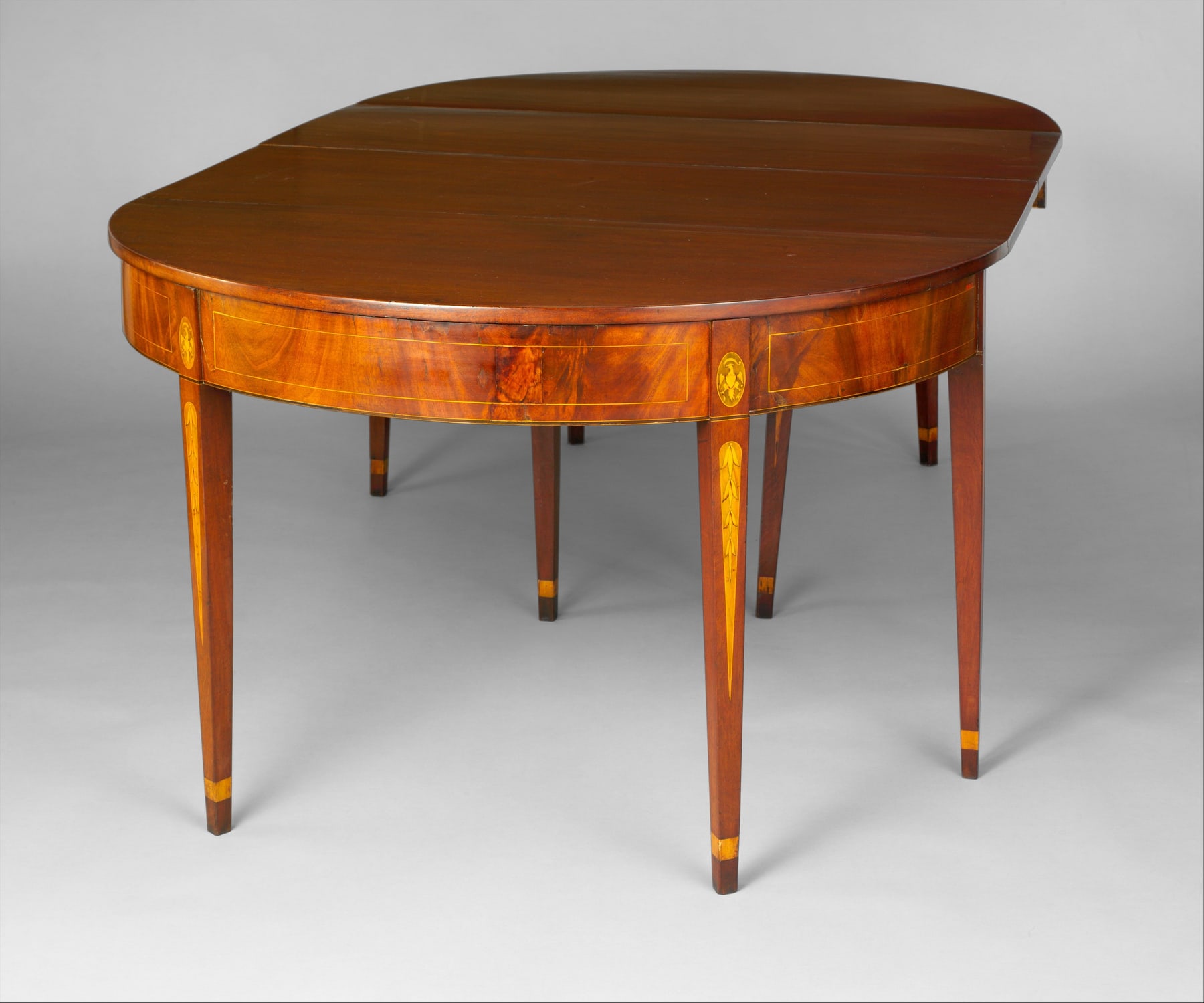 Baltimore dining table assembled from two curved end sections with their rectangular leaves extended.