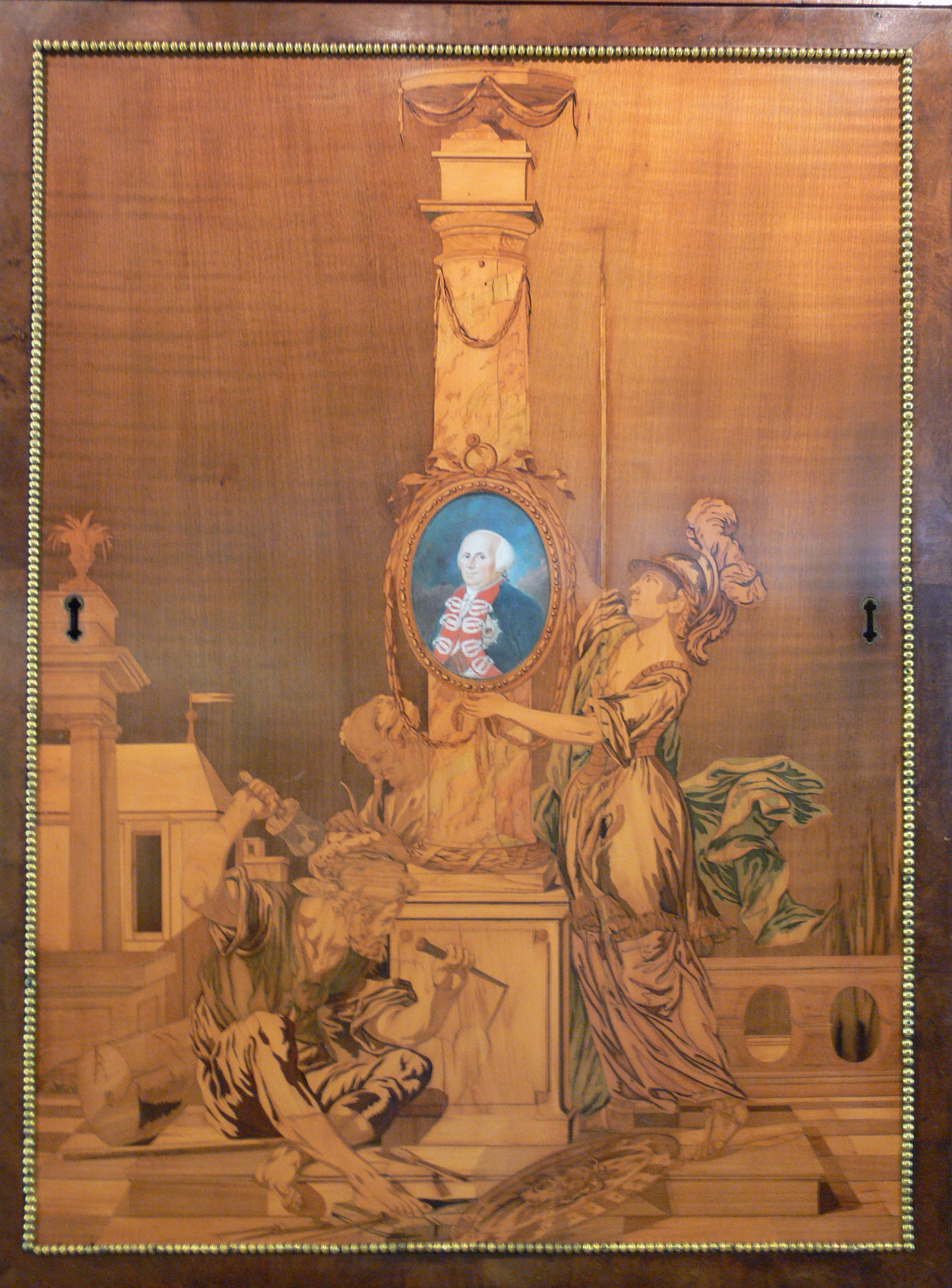 Close view of the cabinet's central marquetry door, with a royal portrait medallion surrounded by allegorical figures.