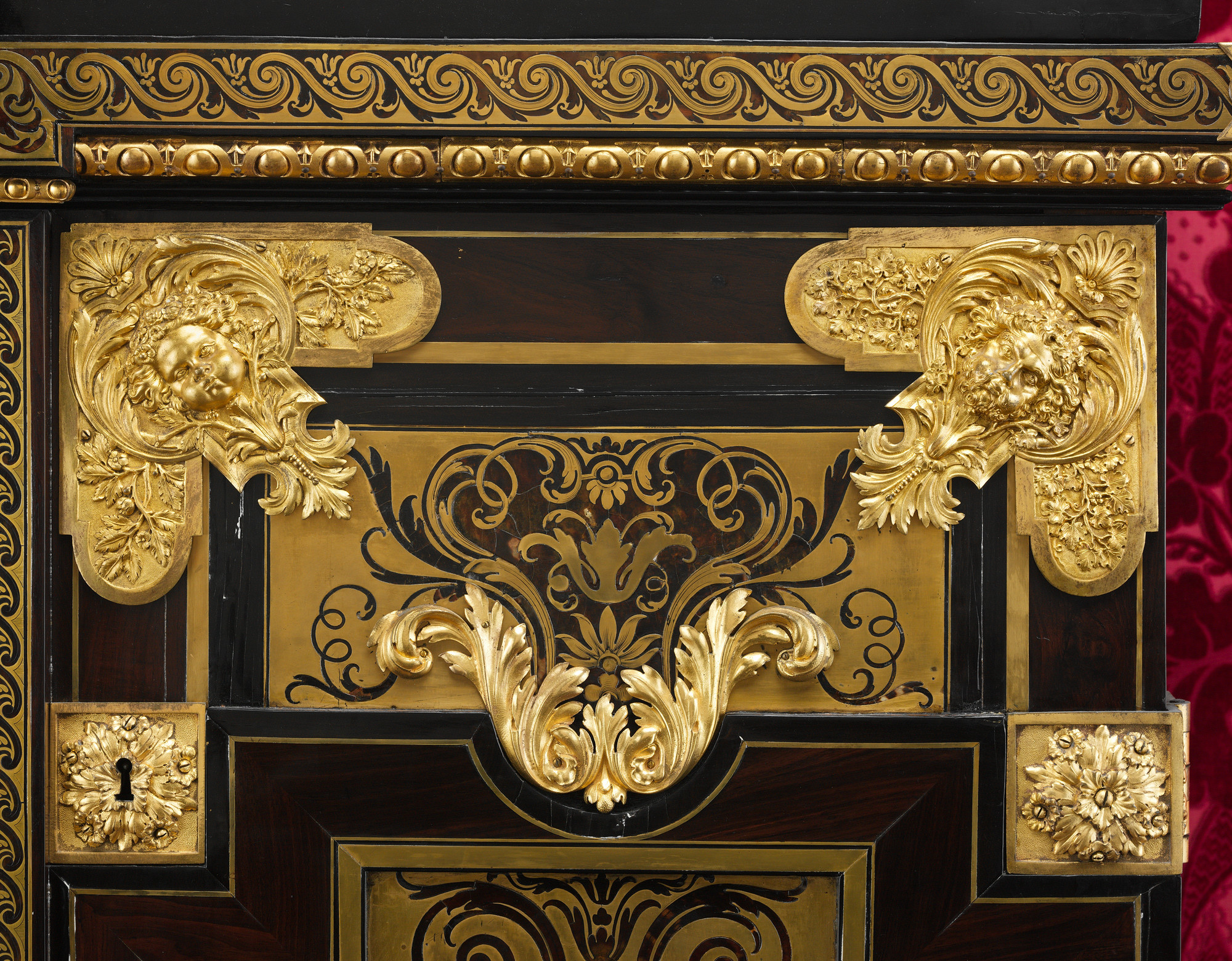 Wide detail of cabinet 59.108 showing brass and tortoiseshell marquetry, gilt-bronze masks, scrolls and the keyhole.