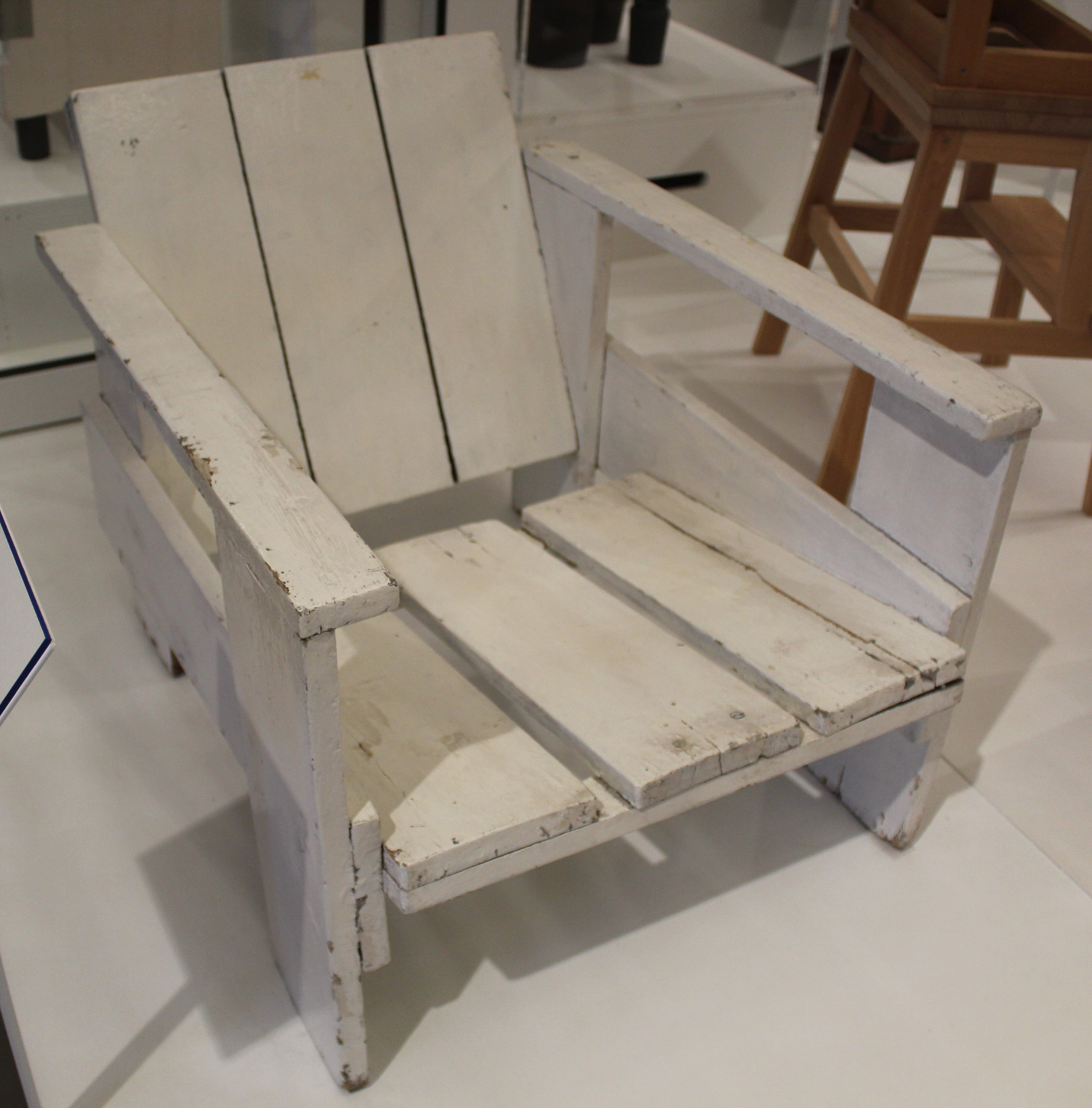 A white-painted wooden Crate Chair at the Victoria and Albert Museum, with broad boards and open sides.