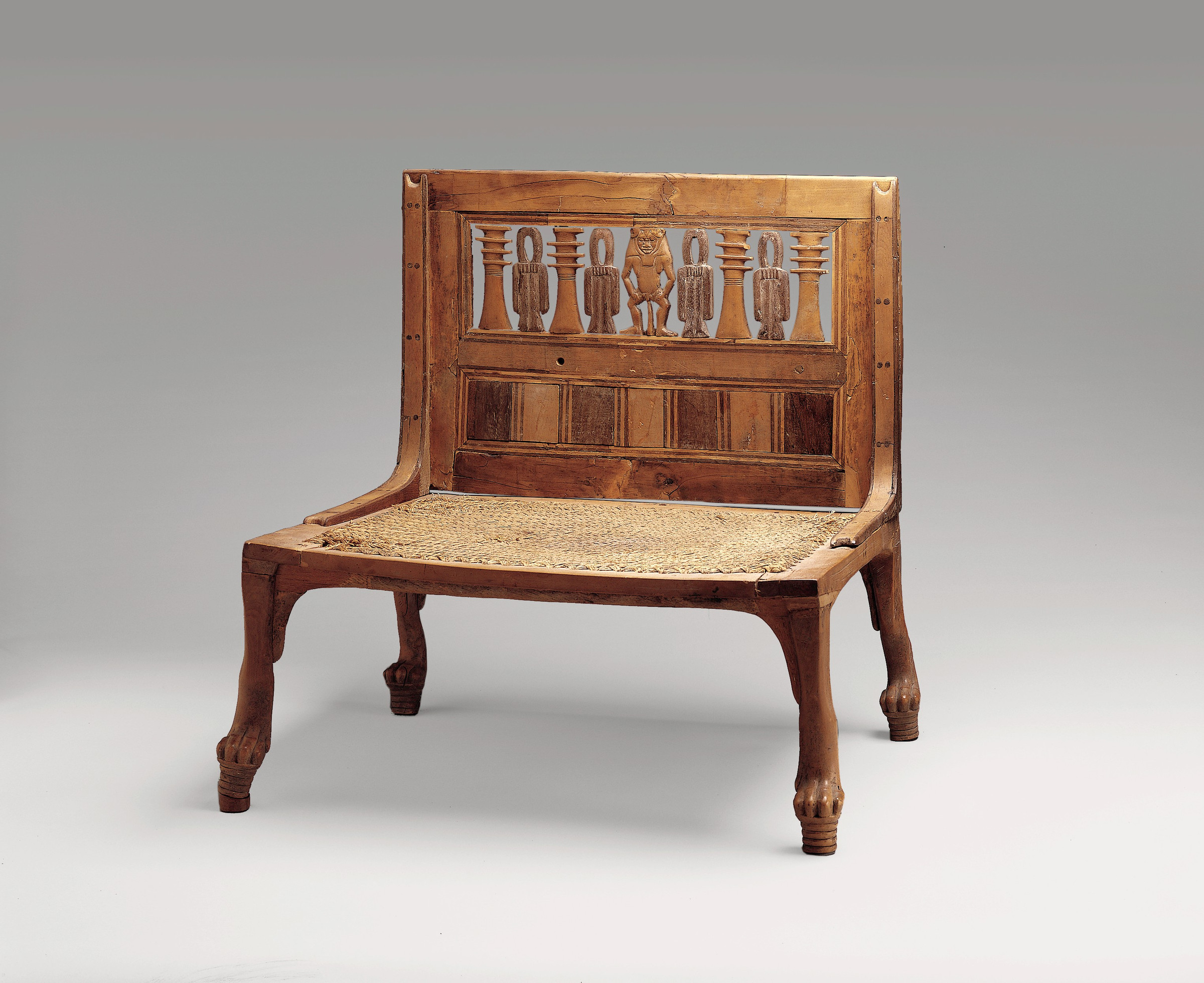 Near-frontal view of Hatnefer's low chair showing the woven seat, pegged frame, back braces and symmetrical protective symbols.