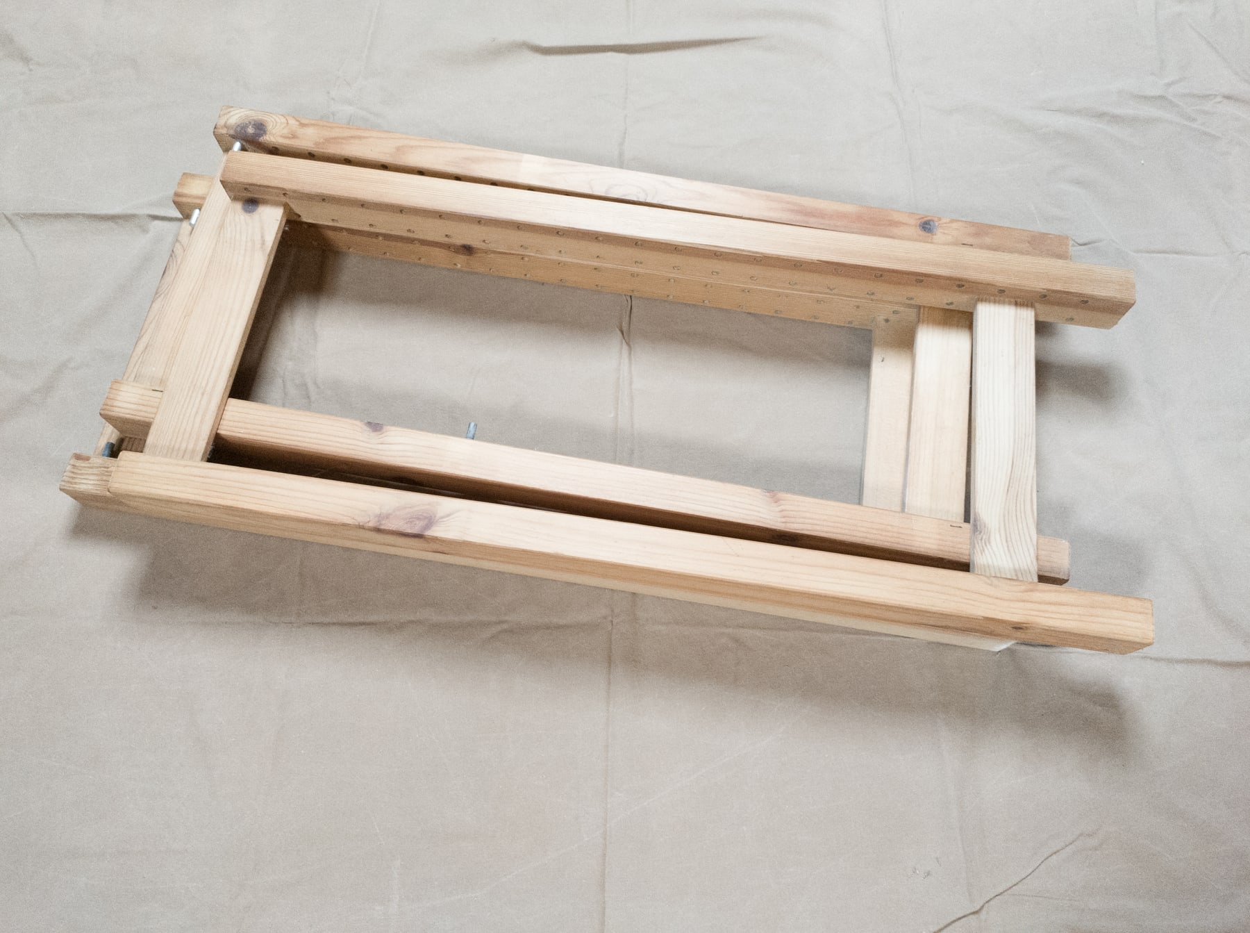 Several unassembled pine IVAR side frames stacked beside a wall, with repeated shelf-pin holes visible along the uprights.