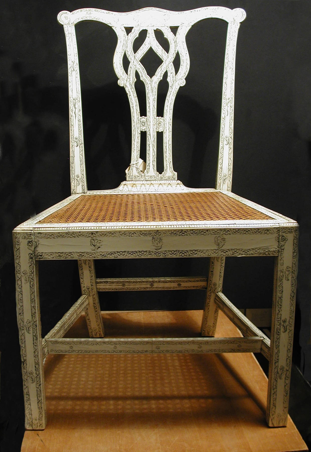 Closer museum view of the Indian-attributed chair, showing the cane seat and the open structure of rails below it.