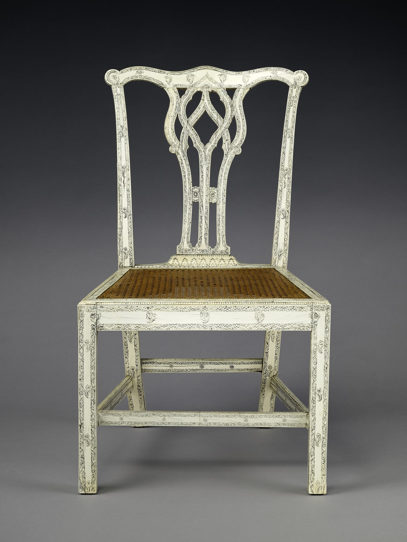 Pale eighteenth-century chair attributed to India, with a pierced back, decorated frame and woven cane seat.