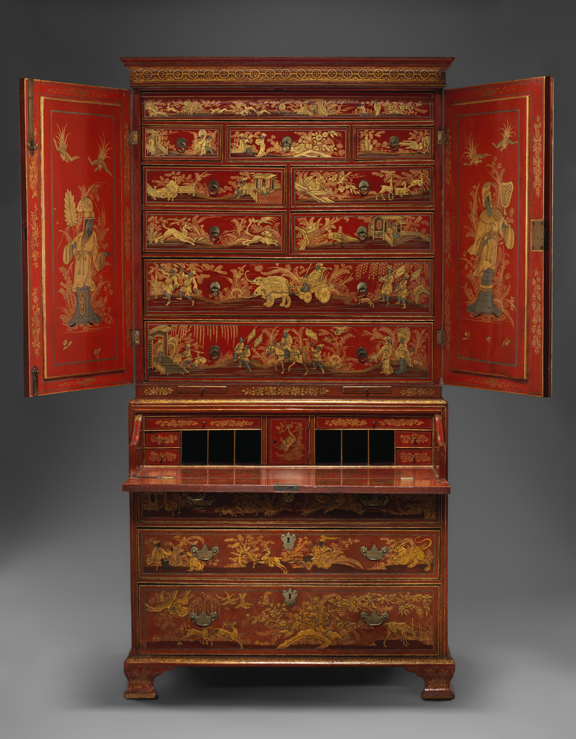 Full frontal view of a tall red japanned secretary cabinet opened to reveal painted upper drawers and a lowered writing surface.