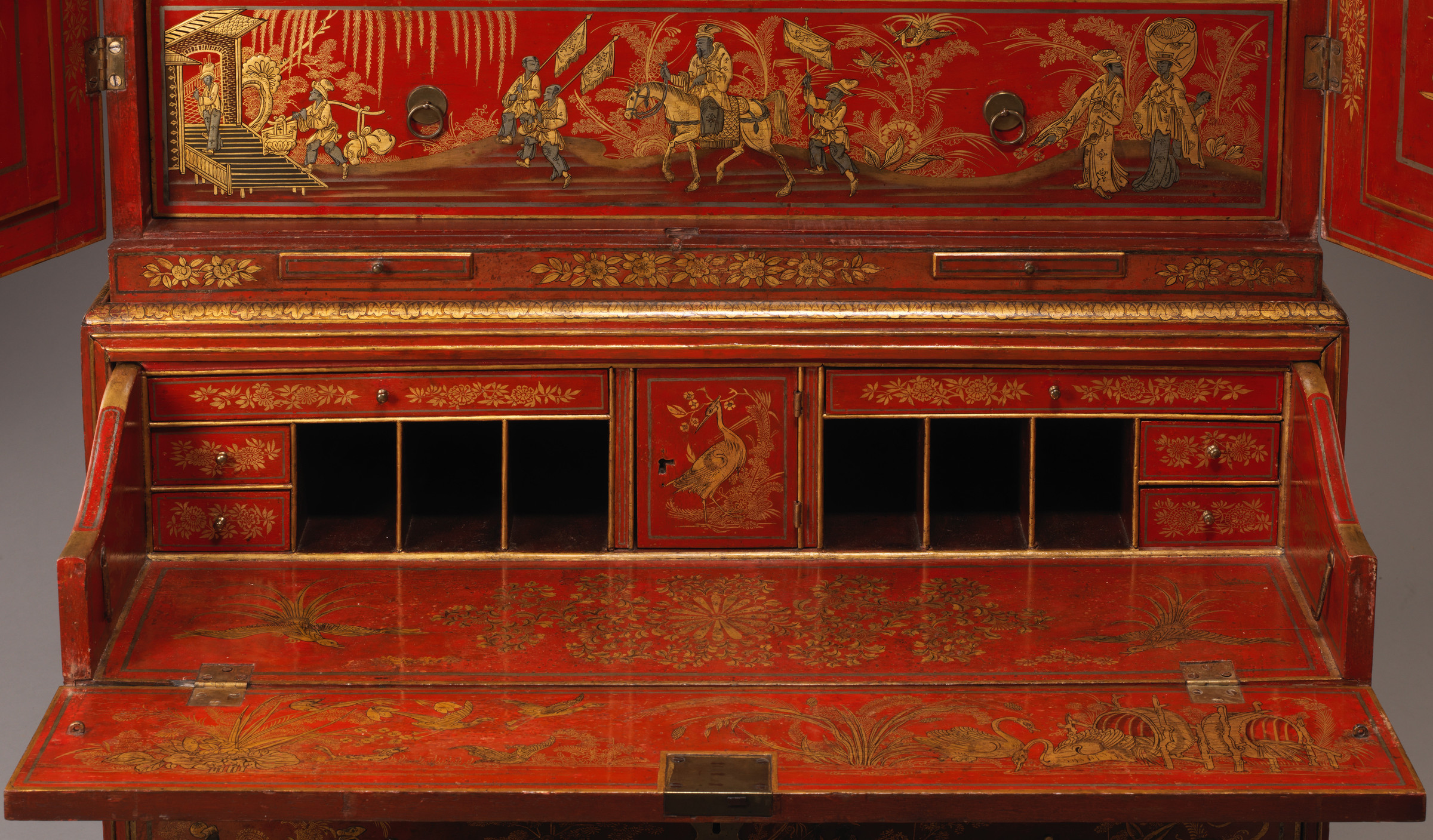 Close frontal view of the secretary's lowered writing leaf, small side drawers, dark pigeonholes and painted panel above.