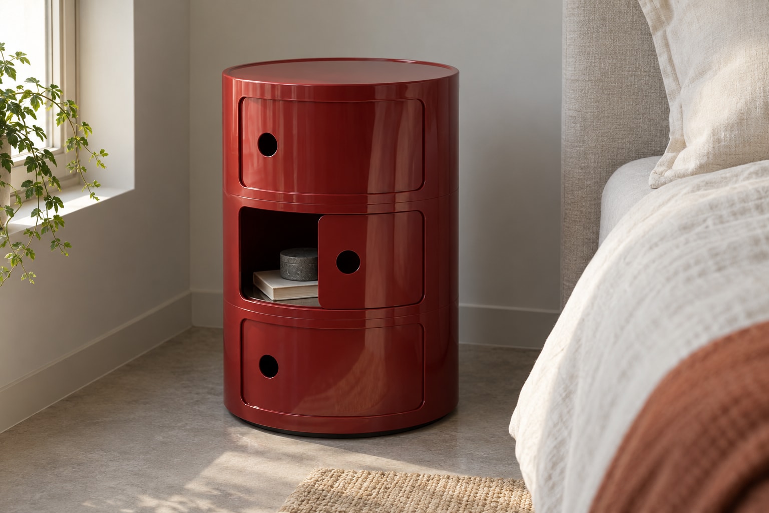 Editorial reconstruction: A rounded burgundy storage unit with three stacked compartments and curved sliding doors beside a bed.