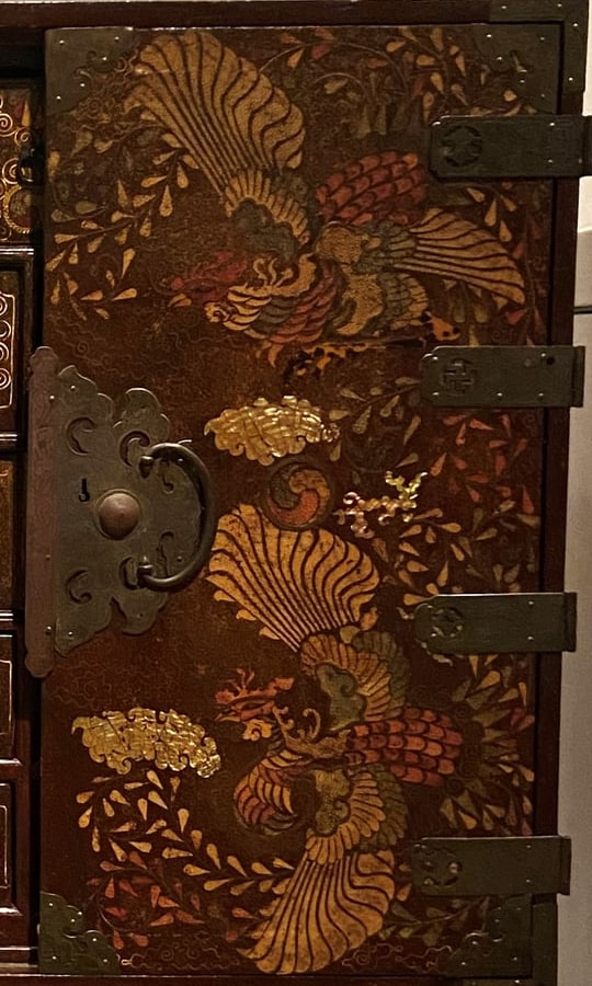 Cropped detail of the closed right door, showing phoenixes, flowers and metal fittings across the inlaid surface.