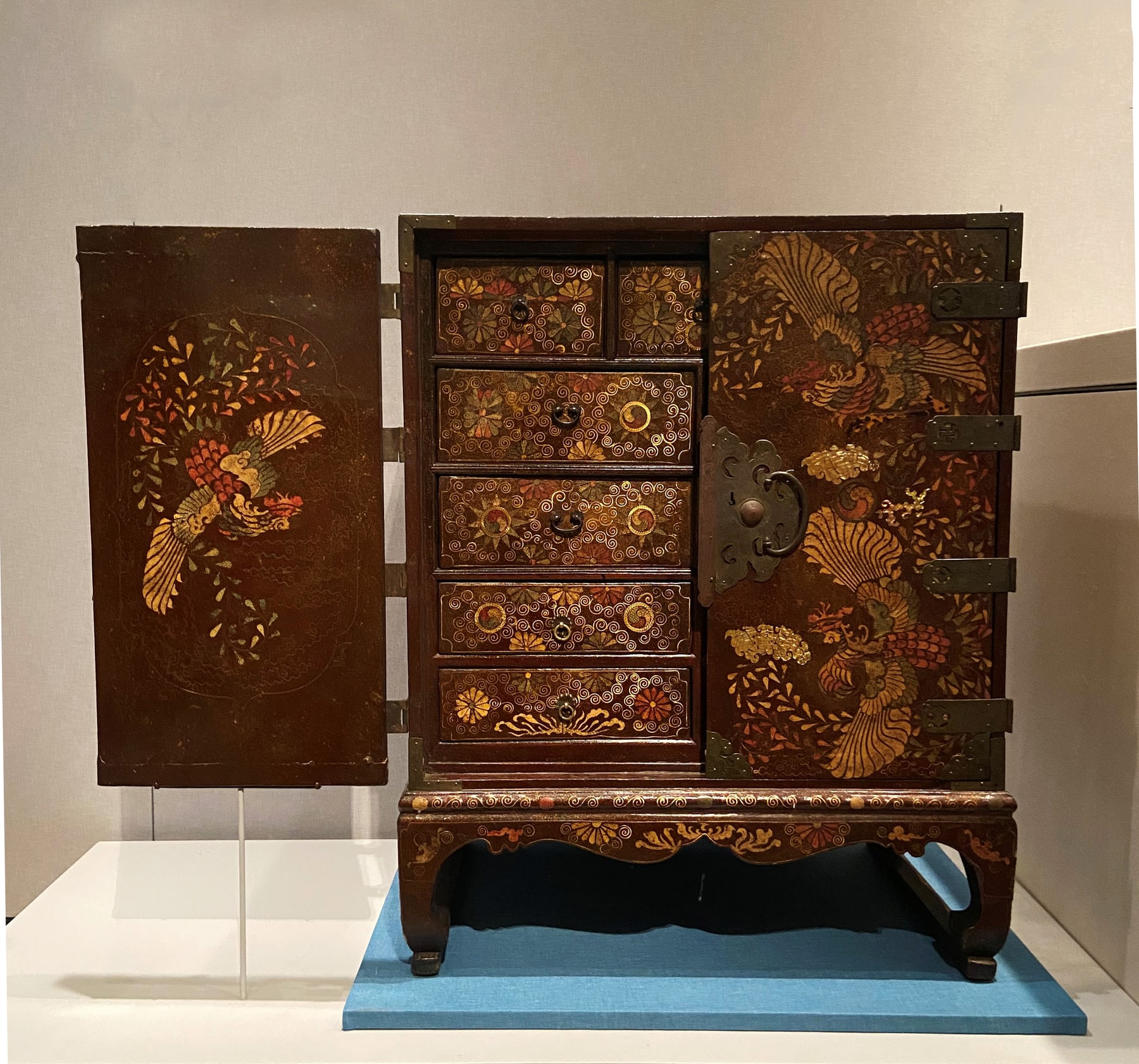 Korean inlaid chest in a museum installation, with the left door open and phoenix decoration visible on the right.