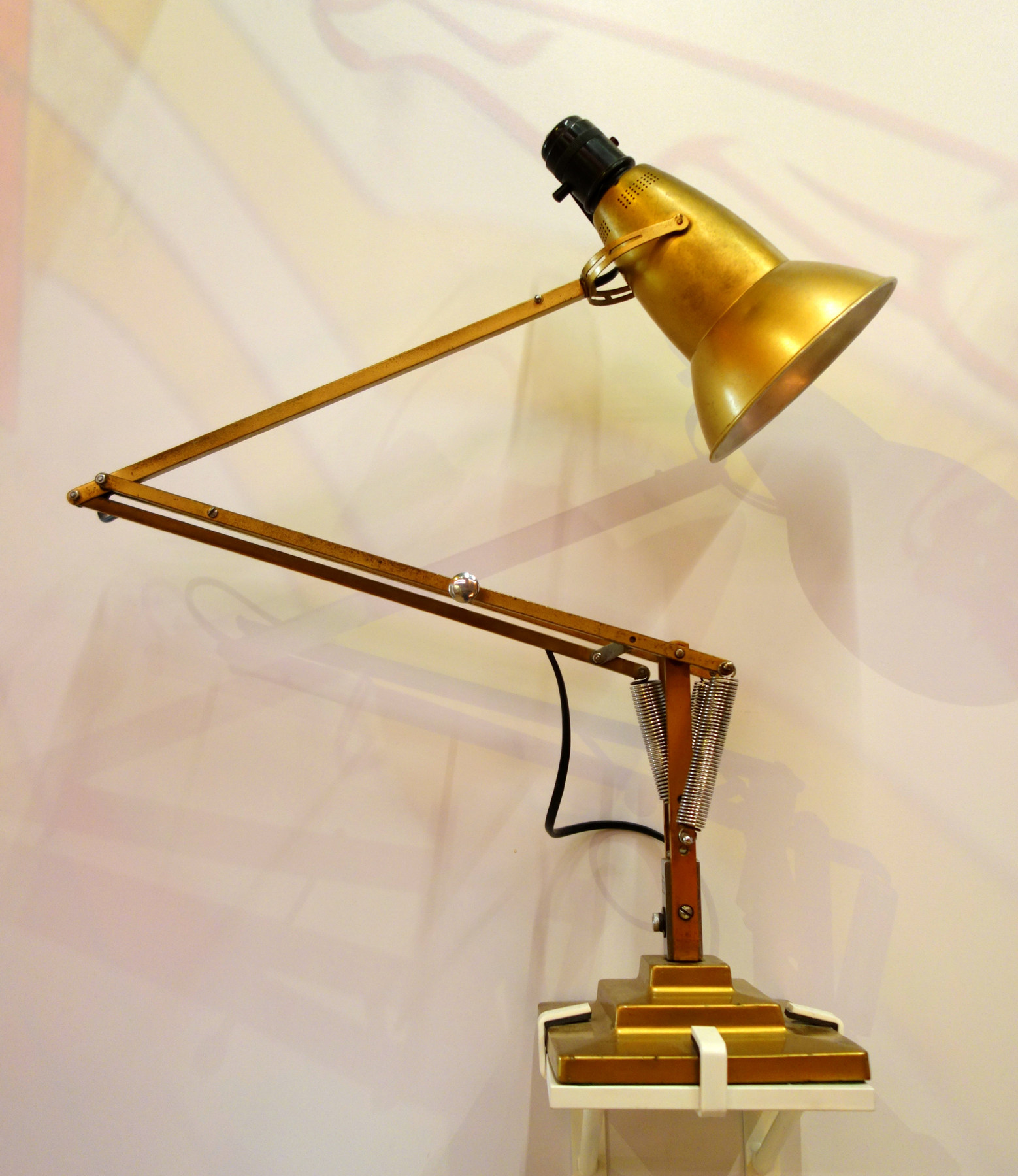 A brass-coloured Type 1227 Anglepoise lamp displayed with its articulated arms extended, clustered springs and stepped base visible.