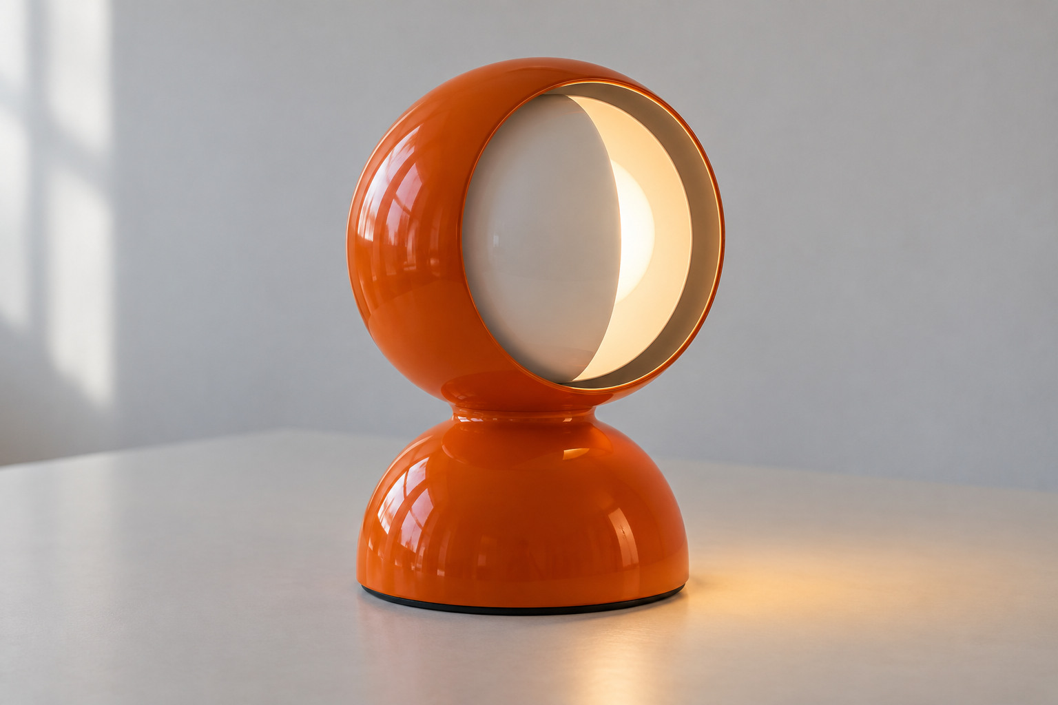 An orange lamp with a rounded base and spherical head shows a white inner shade partly masking the warm light opening against a quiet neutral background.