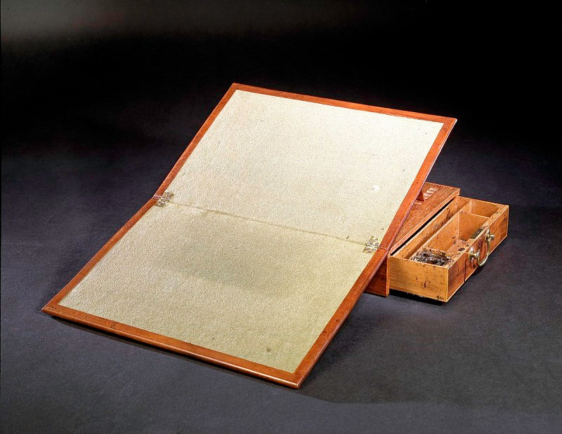 Jefferson’s small mahogany writing desk stands open with a pale baize-covered writing board raised above the case and an inkwell compartment beside it.