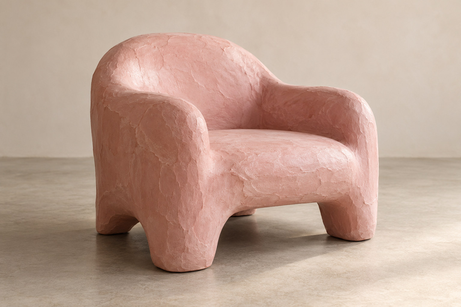 A rounded pink armchair has broad arms and a continuous irregular-looking outer surface.