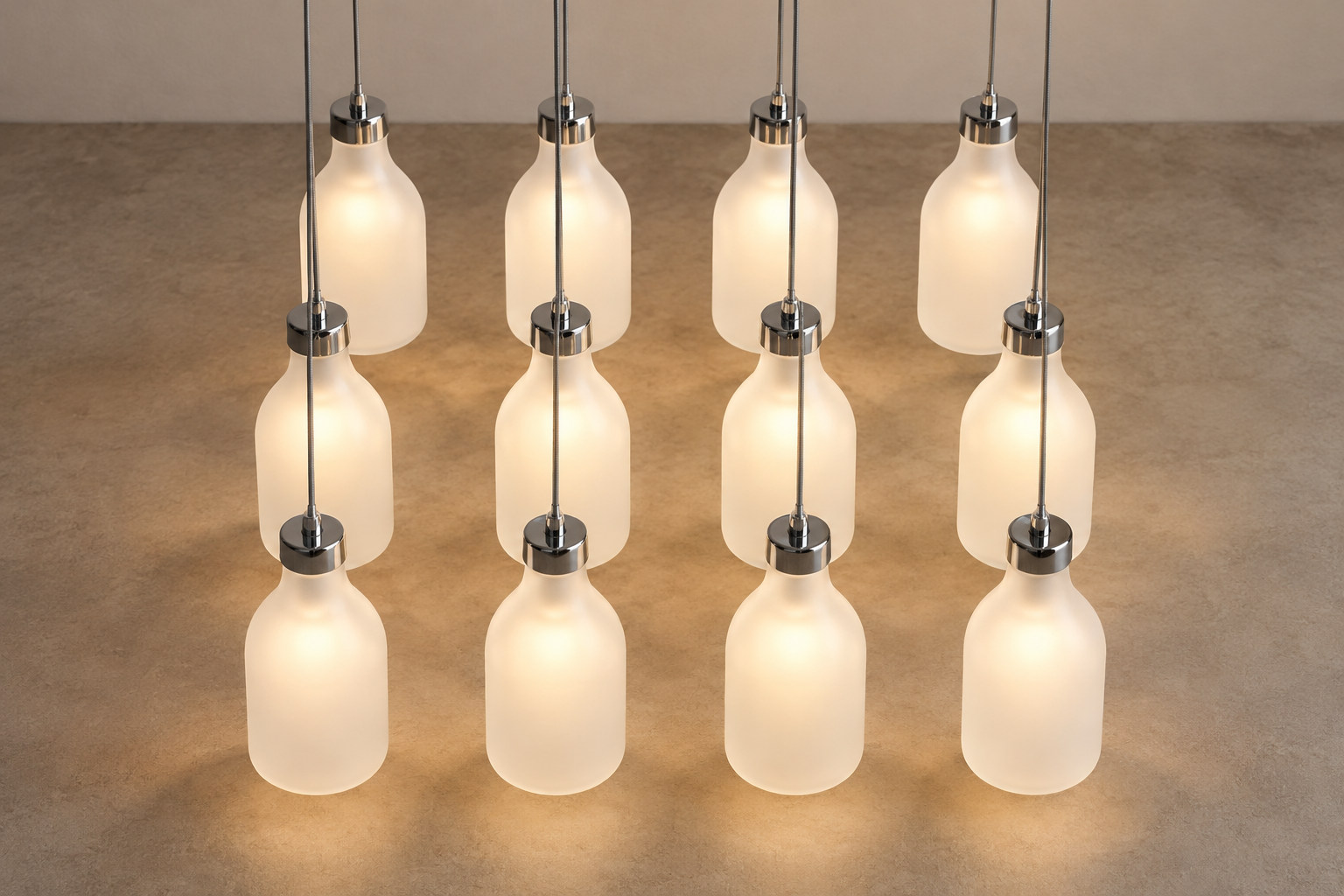 Twelve frosted bottle-shaped lights hang low above the floor in three rows of four.