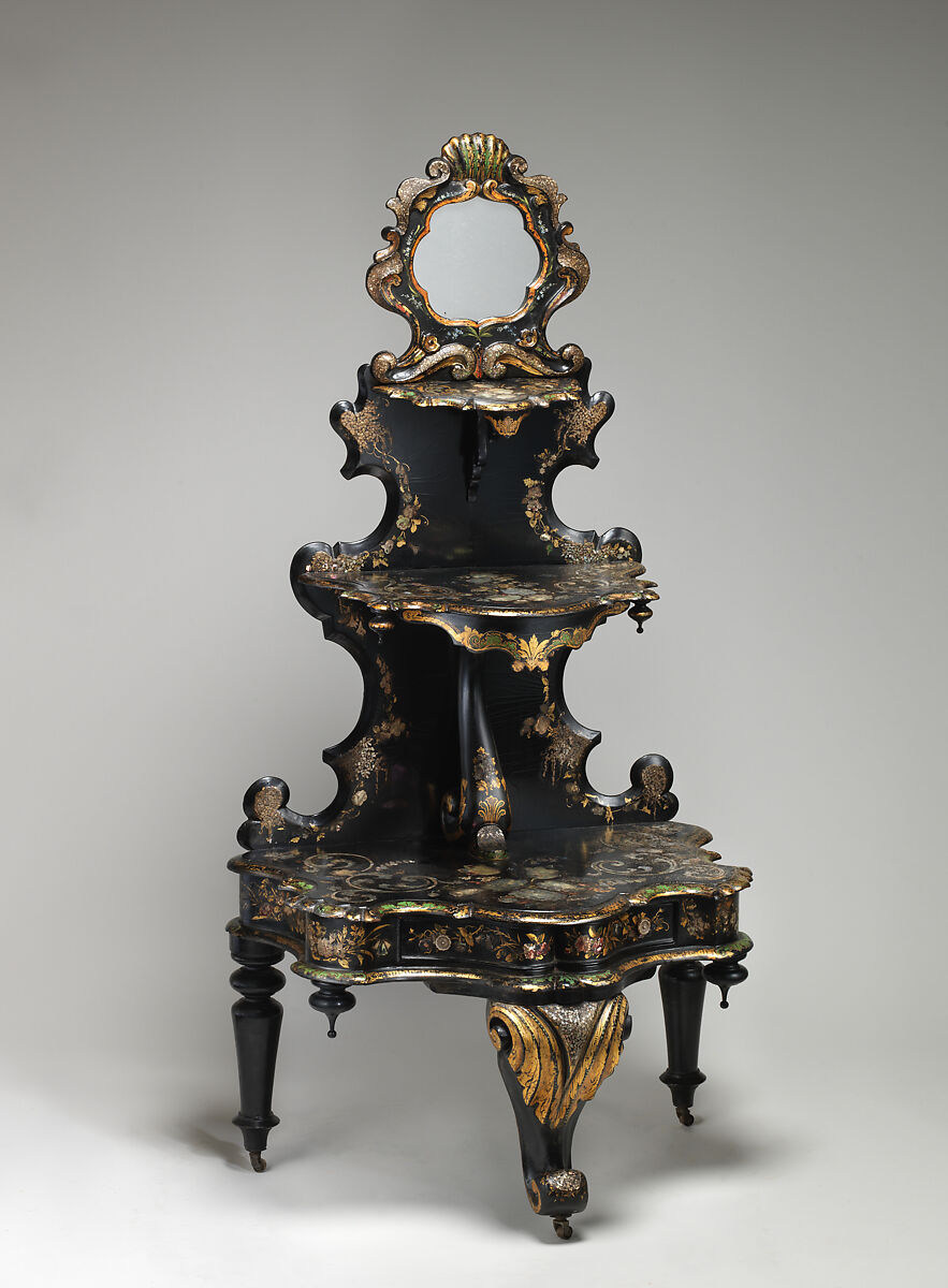 An ornate black and gold three-tier display stand with a mirror, mother-of-pearl details and small castors beneath the base.