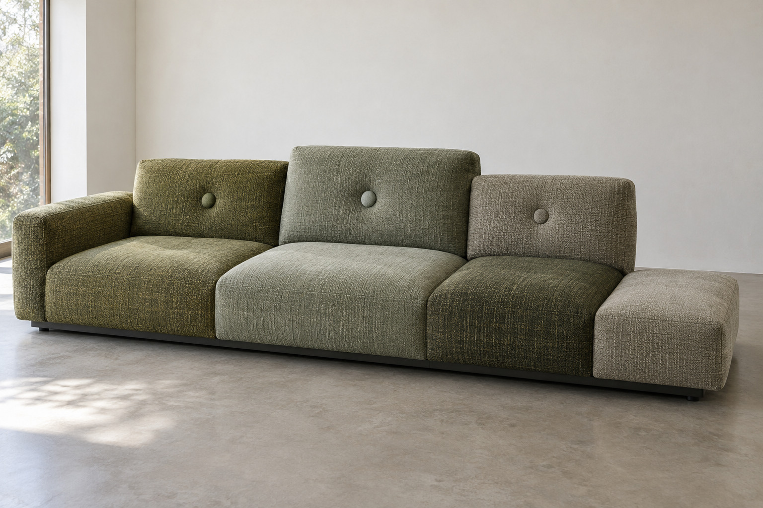 A long low green sofa combines differently textured seat and back cushions with unequal ends.