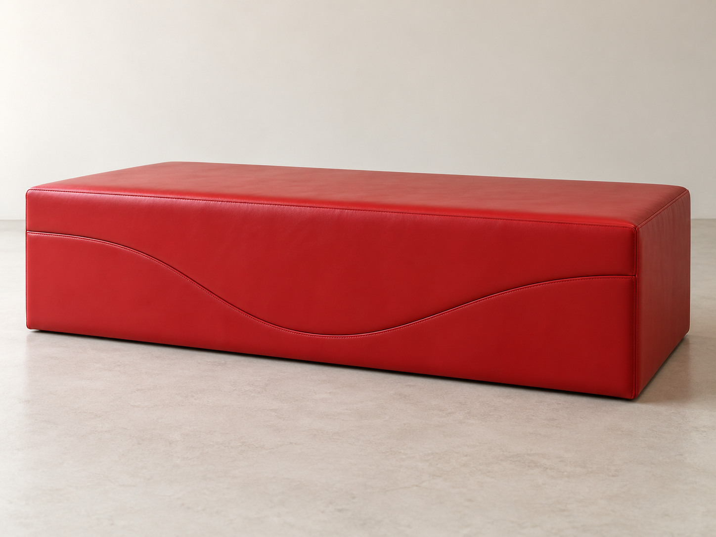 A closed red upholstered rectangular block has a single undulating seam dividing its long side into two fitted sections.