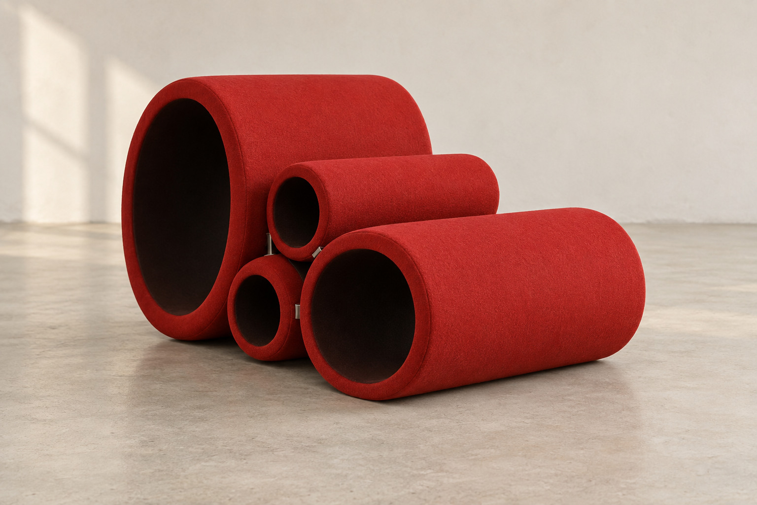 Four red upholstered hollow cylinders of different diameters form a low seating arrangement, with open ends visible and small metal connectors between them.