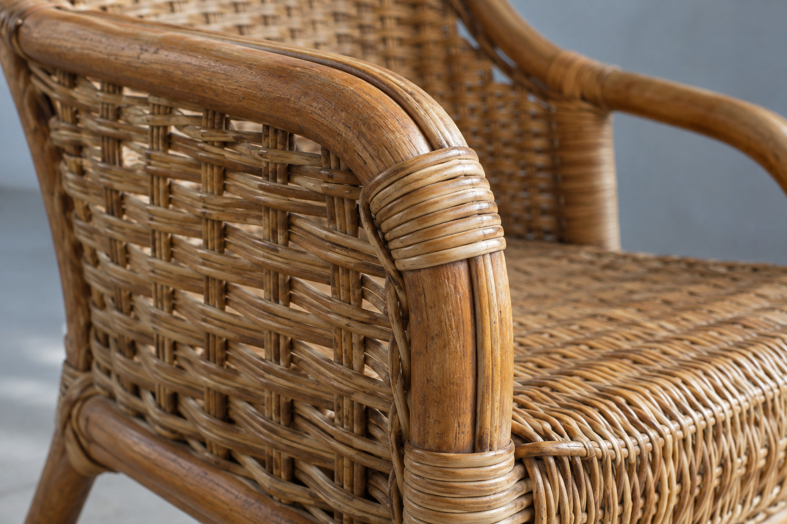 A close view separates the thick curved chair frame, narrow interlaced strands and tight wrapping around a joint.