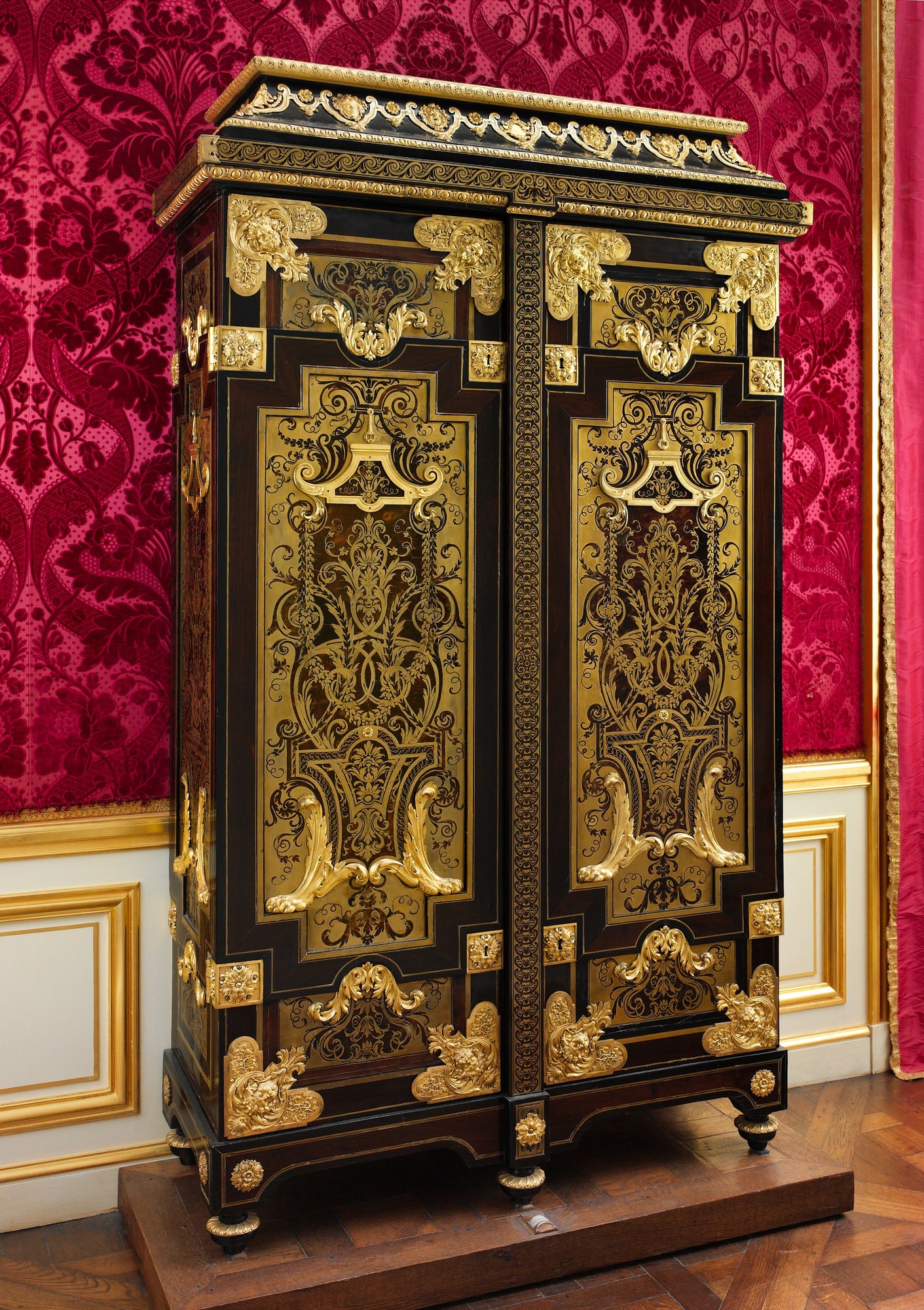 Full view of a tall cabinet attributed to André-Charles Boulle, covered with brass and tortoiseshell marquetry and gilt-bronze mounts.