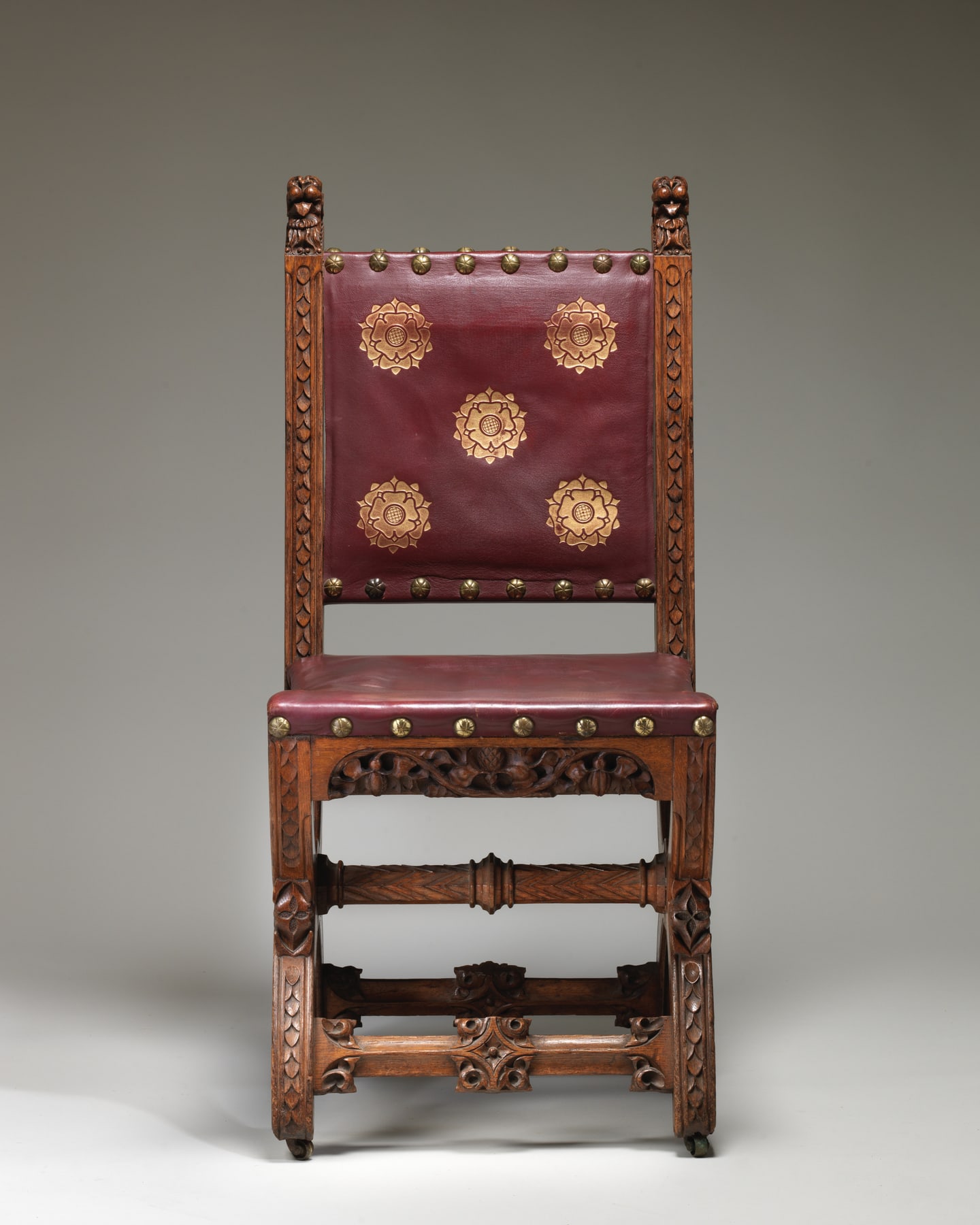 Frontal view of the Speaker’s House chair, showing the carved oak frame surrounding stamped and gilded modern leather.