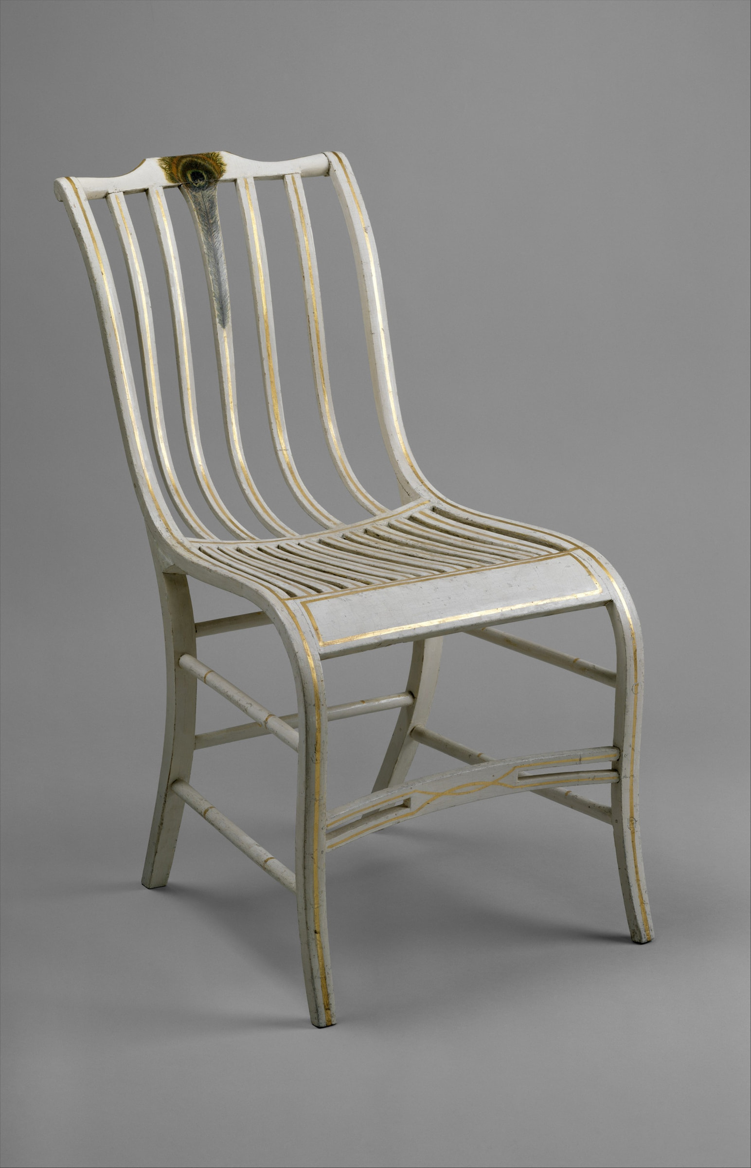 Three-quarter view of Samuel Gragg's white-and-gold side chair with a peacock feather on its crest and thin wooden strips curving through back and seat.