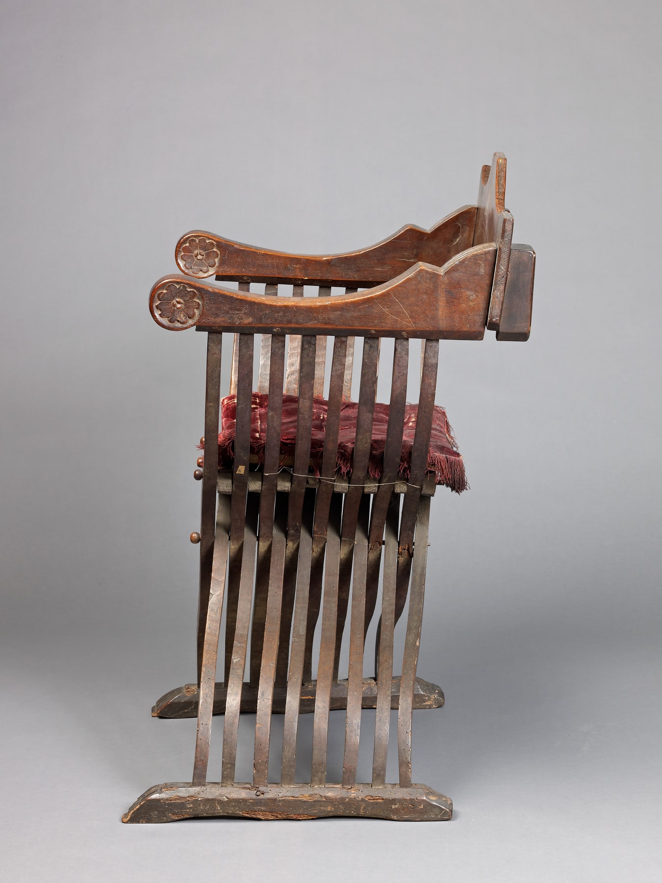 Side view of the Savonarola chair, showing parallel curved members passing through the central crossing.