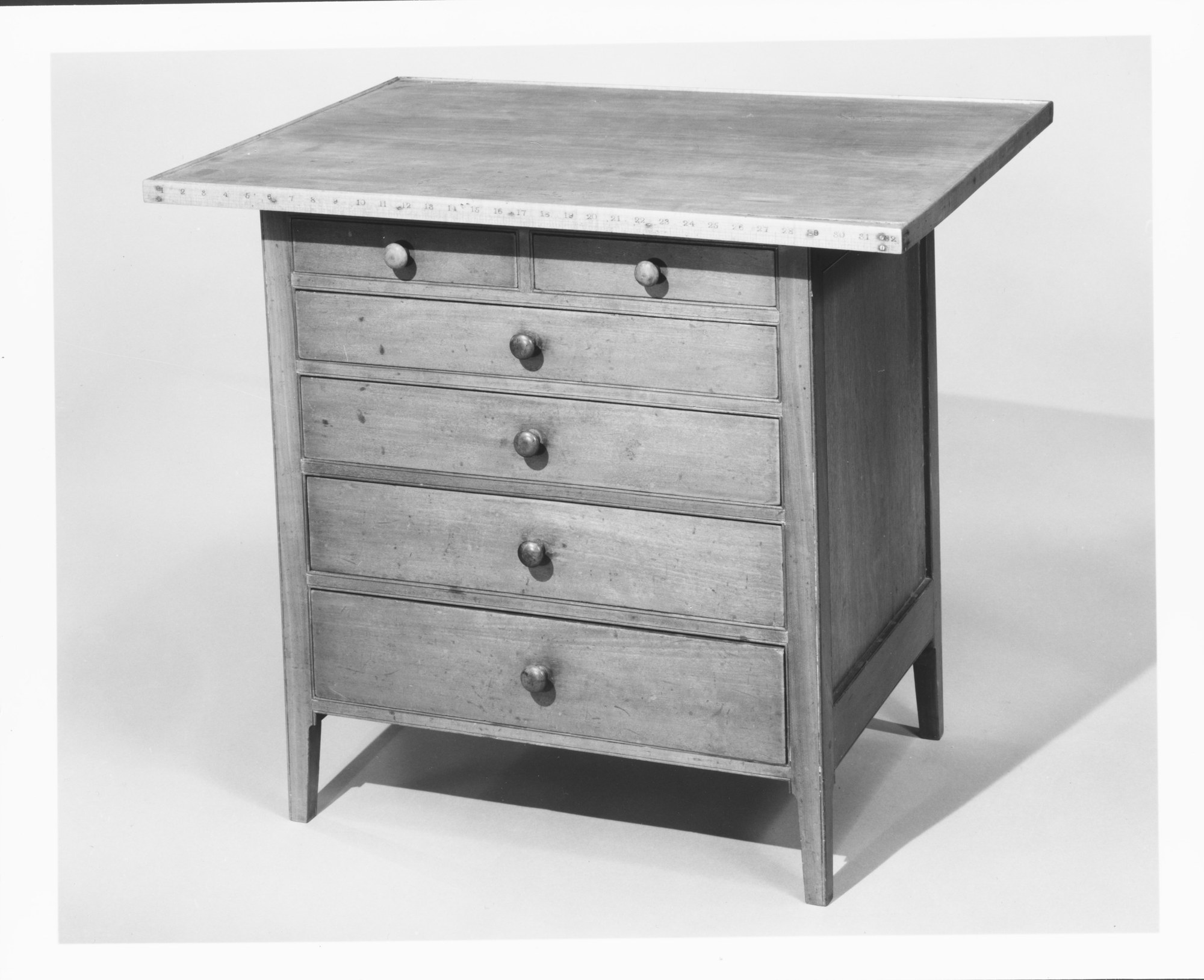 Older black-and-white museum photograph of Shaker sewing table 66.10.18, viewed from the front and right side.