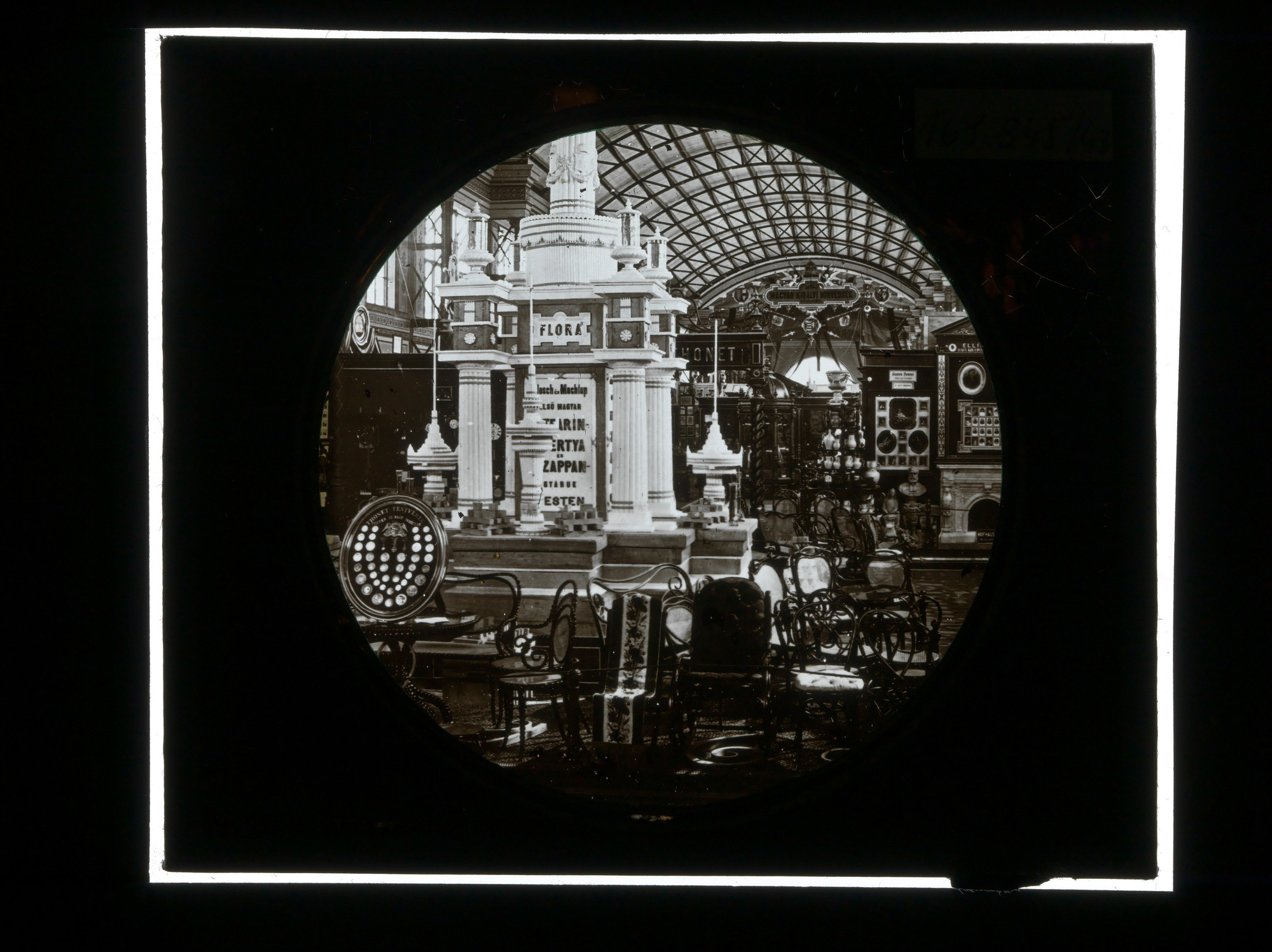 Black-and-white 1873 exhibition photograph showing a dense display of Thonet furniture beneath the Vienna World's Fair hall roof.