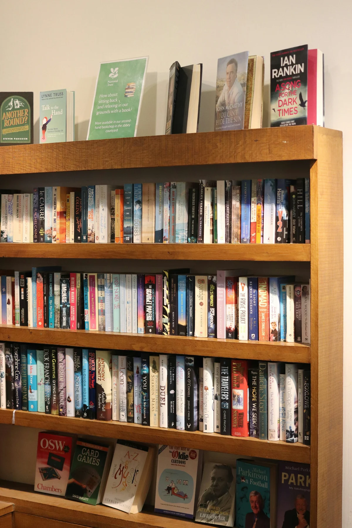 Wooden bookcase filled with upright books and larger face-out volumes that conceal some of the shelf connections.