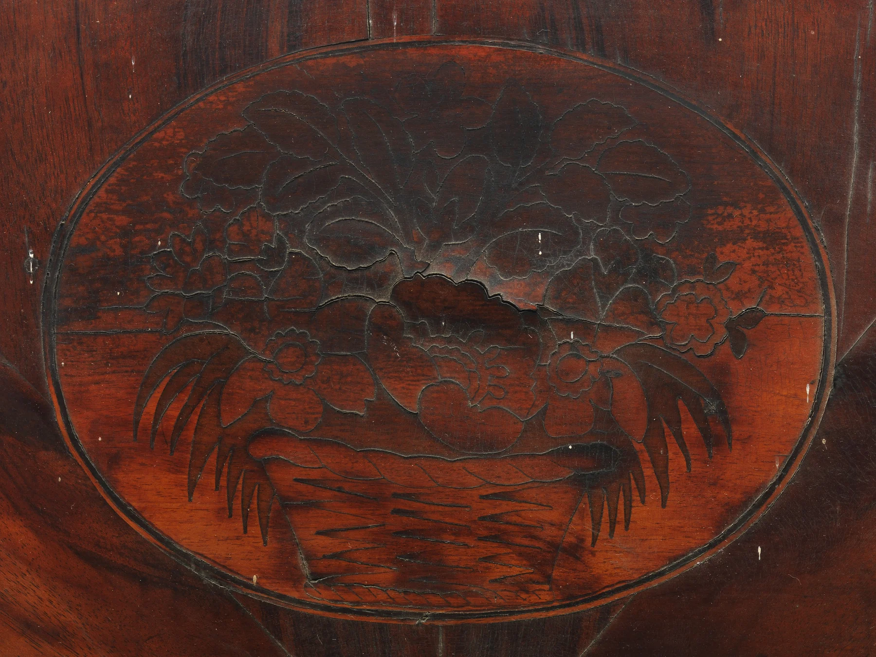 Close view of the chair's half-round crest with radiating mahogany veneer, a central flower-basket inlay and a light-dark border.