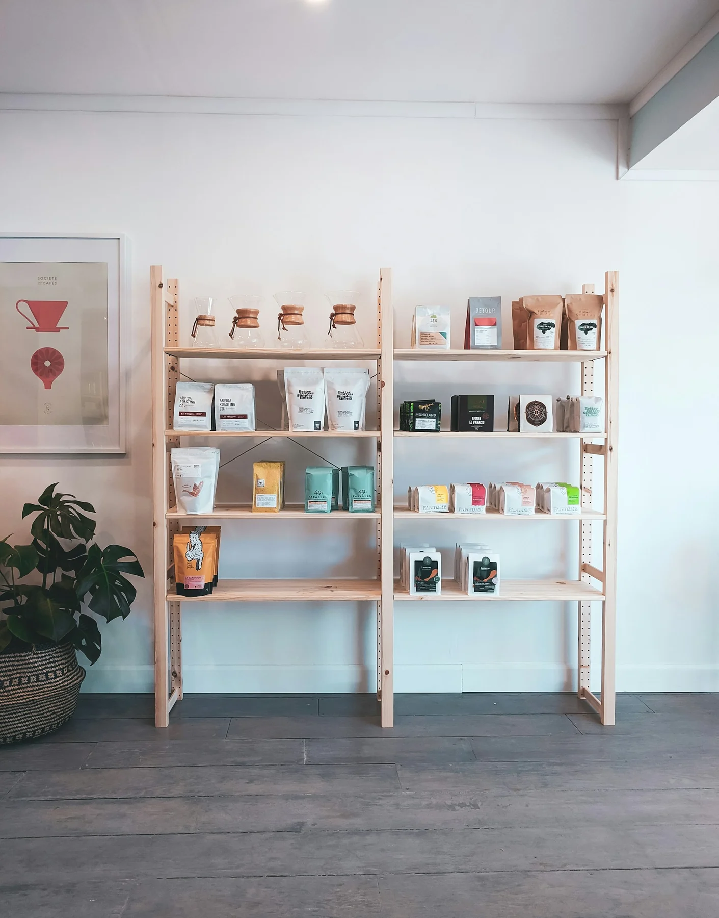Two bays of open wooden shelving against a wall, with a diagonal metal cross-brace visible behind the shelves.