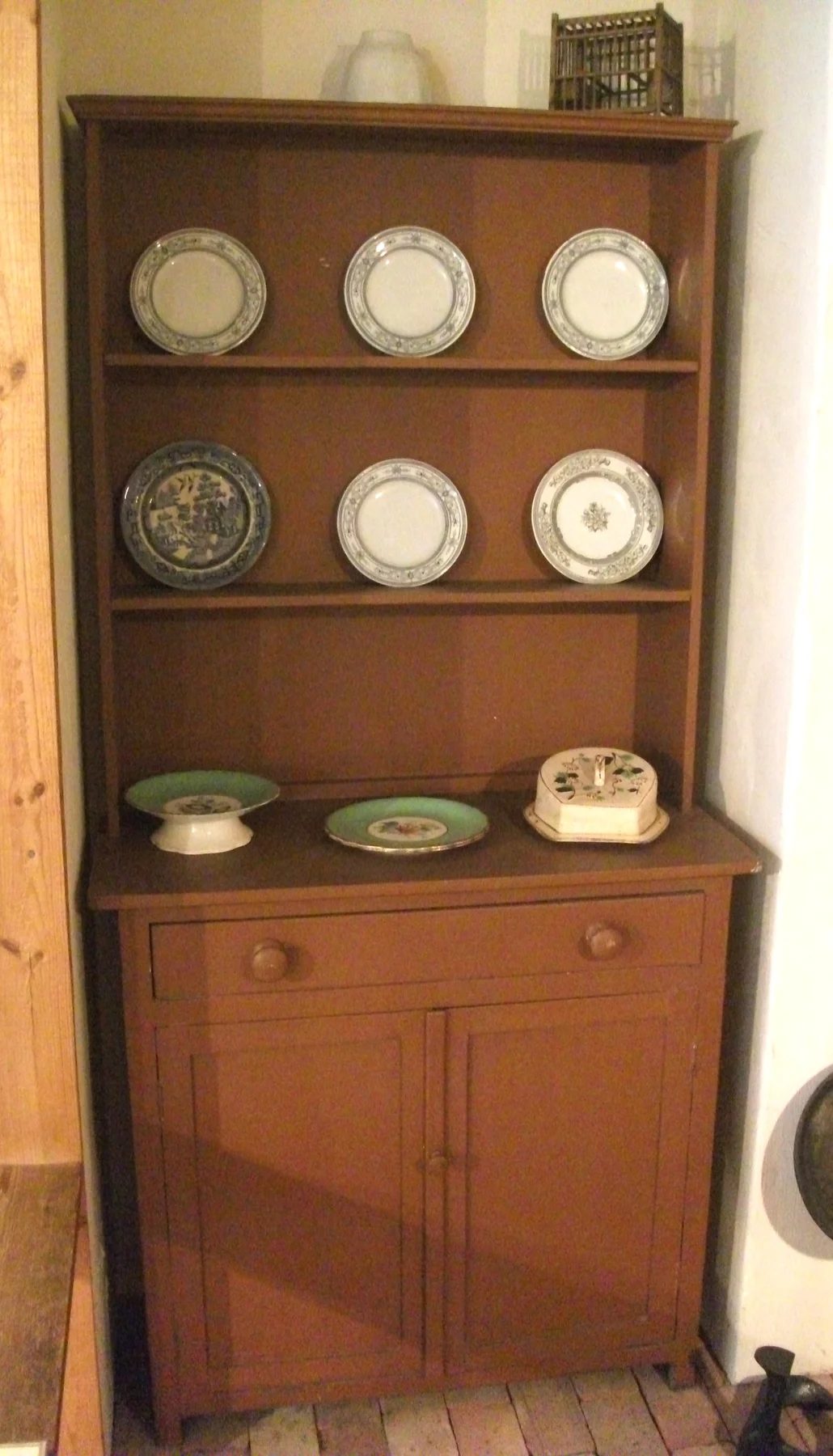 Wooden Welsh dresser with an open plate rack above a drawer and two cupboard doors.