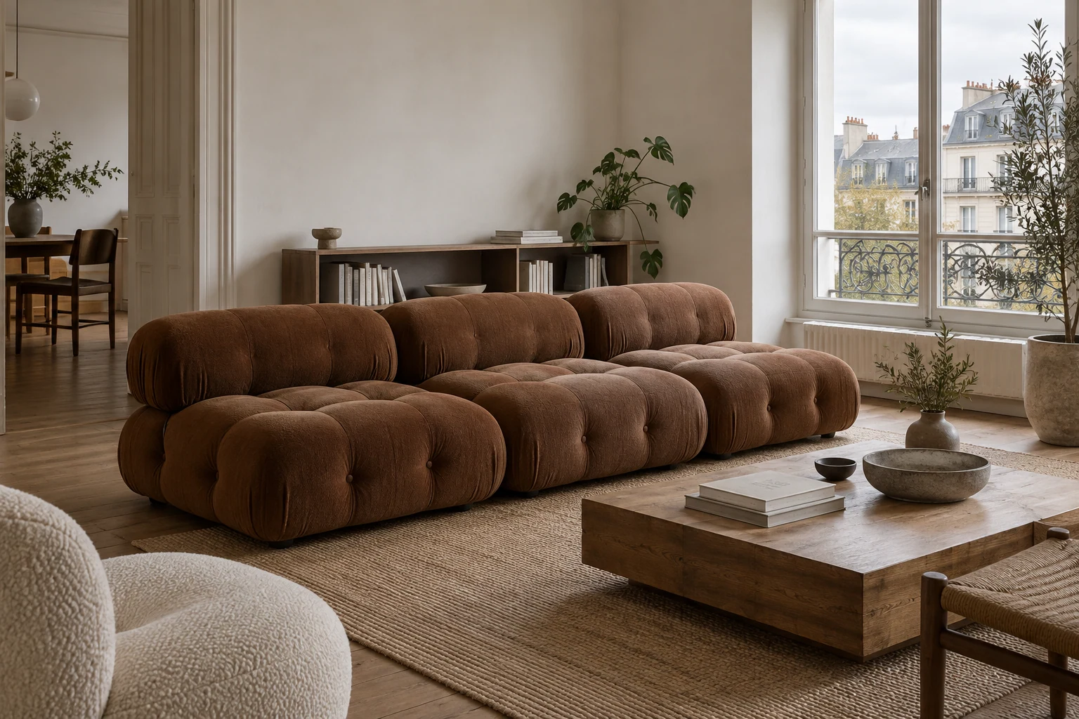 A low brown modular sofa stands beside a timber coffee table in a bright living room.