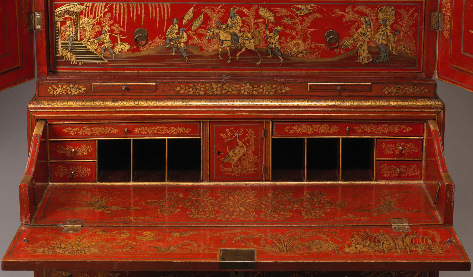 Close frontal view of the secretary's lowered writing leaf, small side drawers, dark pigeonholes and painted panel above.