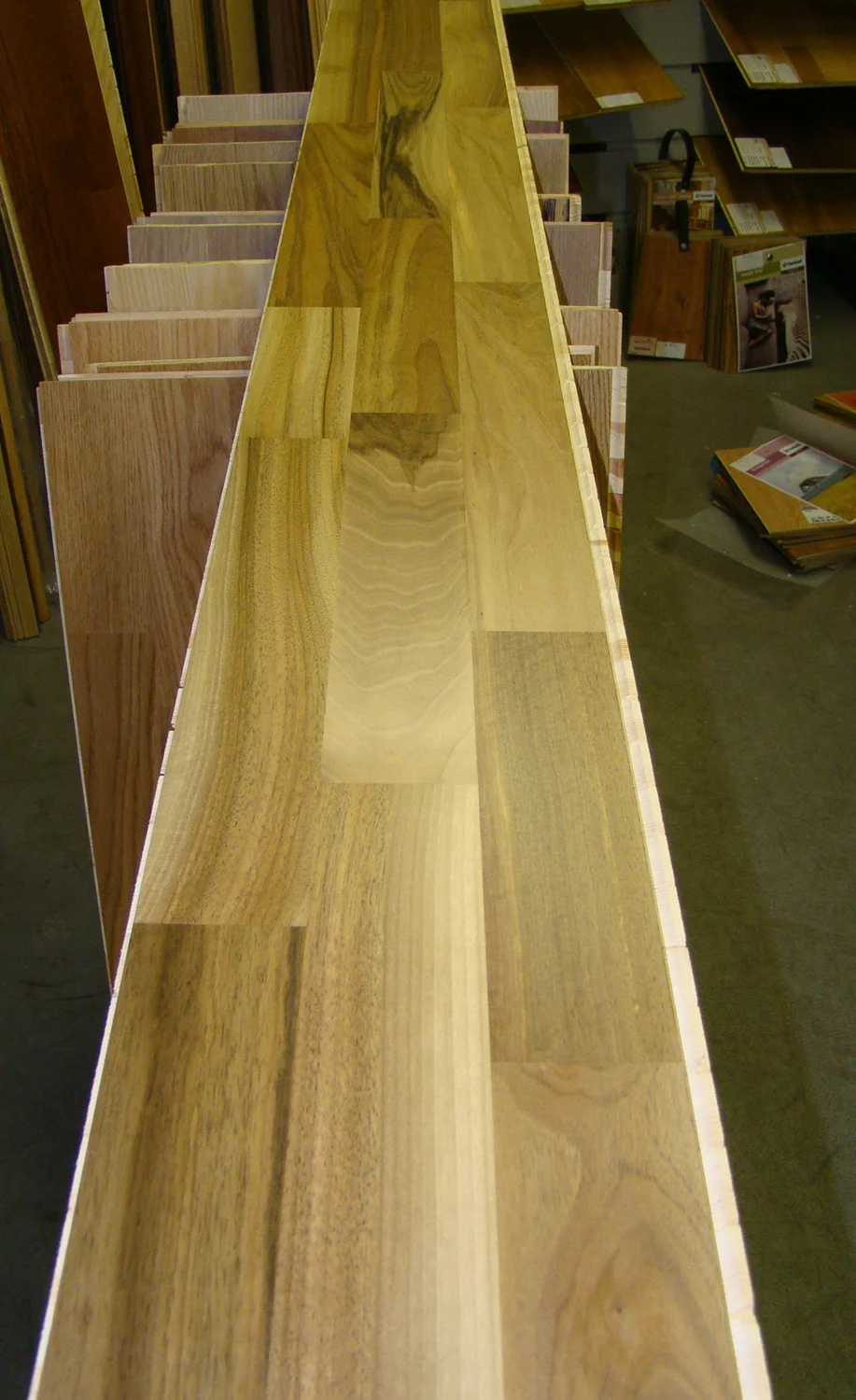 Contributor-identified walnut parquet sample showing contrasting strips and changing figure in a flooring shop.