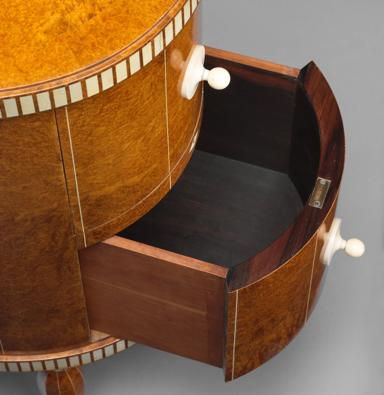 Detail of an open bowed drawer in Ruhlmann’s cabinet, showing a rectangular pale inlay border across the figured veneer.