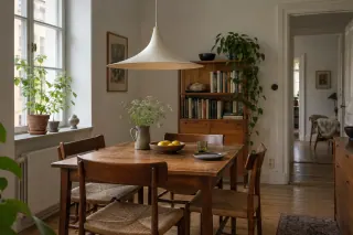 A wide white flared pendant above a wooden dining table.