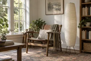A tall ribbed paper floor light beside a wooden chair in a reading corner.