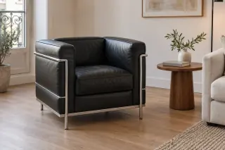 A compact black leather armchair with an external tubular-metal frame stands beside a small side table.