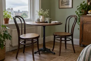 Two dark bentwood chairs with curved backs beside a small round café table.