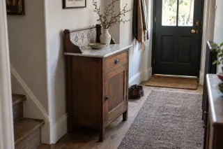 A marble-top wooden washstand with a tiled back used as a hallway cabinet.