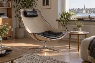 A curved sling-supported reading chair with a separate cushion and neck pillow.