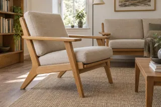 A broad-armed wooden lounge chair with separate pale cushions stands beside a matching sofa.