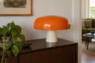 An orange rounded-shade table lamp shown complete on a wooden cabinet.