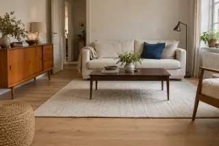 A honey-coloured sideboard and dark brown coffee table share a living room with a pale wooden floor, cream rug and sofa.