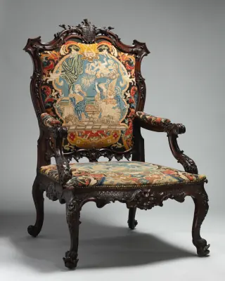 A full front view of an eighteenth-century mahogany armchair with patterned needlework upholstery on its back, seat and arms.