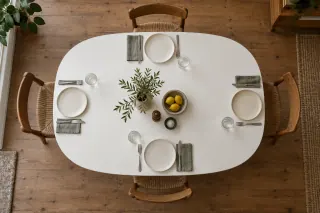An overhead view of a white curved dining tabletop with four place settings.