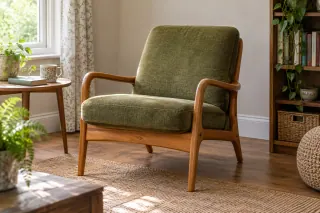 A compact open-frame wooden armchair with separate green seat and back cushions.