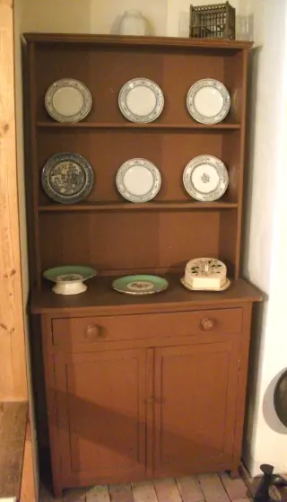 Wooden Welsh dresser with an open plate rack above a drawer and two cupboard doors.